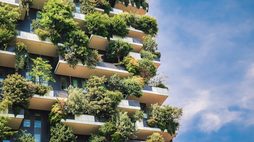 picture depicts a building covered with green plants and balconies in milan, italy